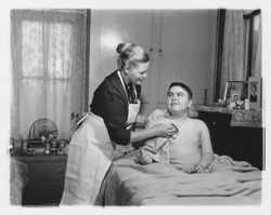Visiting nurse at administers to a boy in his bed at home, Santa Rosa, California, 1960 (Digital Object)