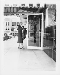 Model in a worsted wool skirt and jacket at the door of the Topaz Room where the &quot;Dramatic Moods&quot; fashion show will be held, Santa Rosa, California, 1959 (Digital Object)