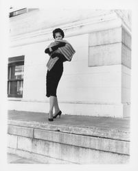 Black pencil dress and fur stole modeled on the ledge of the Sonoma County Courthouse, Santa Rosa, California, 1959 (Digital Object)