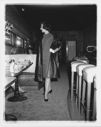 Model in evening dress and a long coat in the &quot;Dramatic Moods&quot; fashion show in the Topaz Room, Santa Rosa, California, 1959 (Digital Object)
